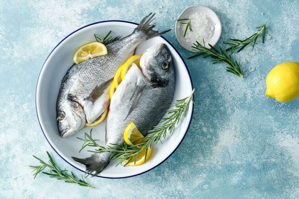 Fresh raw dorado fish cooking with lemon and rosemary. Sea bream, dorado. Seafood, healthy food